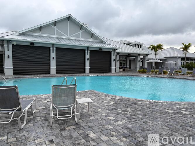 A pool area with chairs and a house in the background.