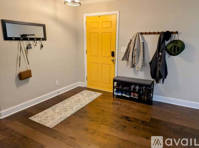 A hallway with a yellow door and a coat rack with several items hanging on it.