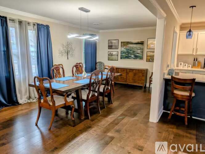 A dining room with a table set for six and a kitchen area in the background.