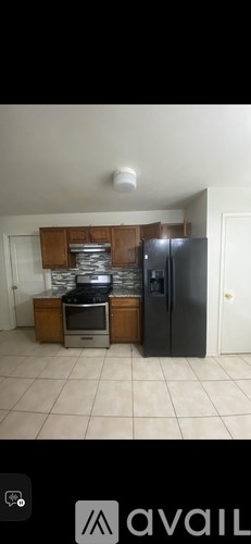A kitchen with a black fridge and wooden cabinets.