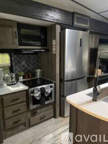 A kitchen with a stainless steel refrigerator and a microwave above the stove.