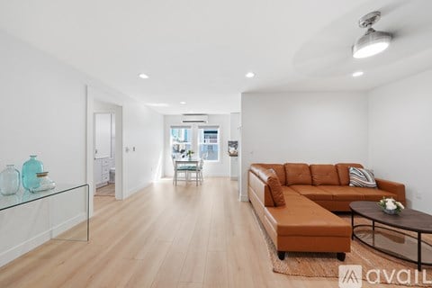 A living room with a brown leather couch and a glass coffee table.
