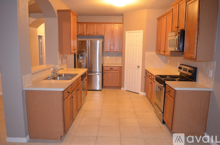 A kitchen with wooden cabinets and a stainless steel refrigerator.
