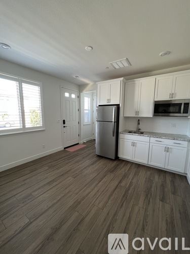 A kitchen with white cabinets and a refrigerator.