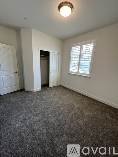 A room with a carpeted floor and a window with blinds.