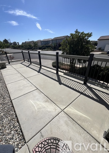 A concrete walkway with a metal railing and a manhole cover on the ground.