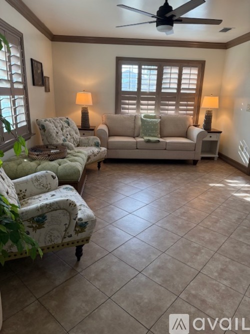 A living room with a couch, chair, and a fan.