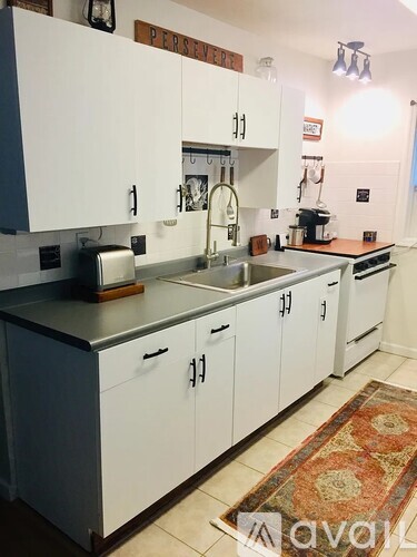 A kitchen with white cabinets and a rug on the floor.