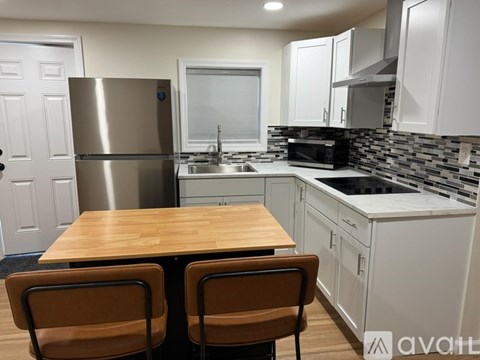 A kitchen with a table and chairs in front of a refrigerator.