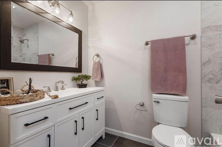 A bathroom with a white toilet and a pink towel.