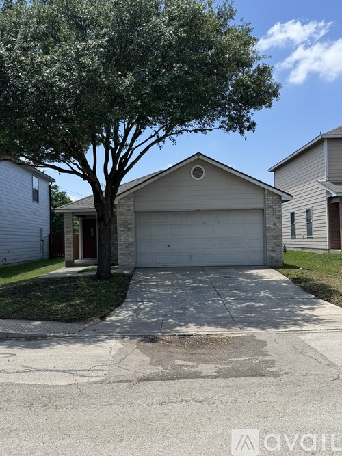 A tree is in front of a garage and a house.