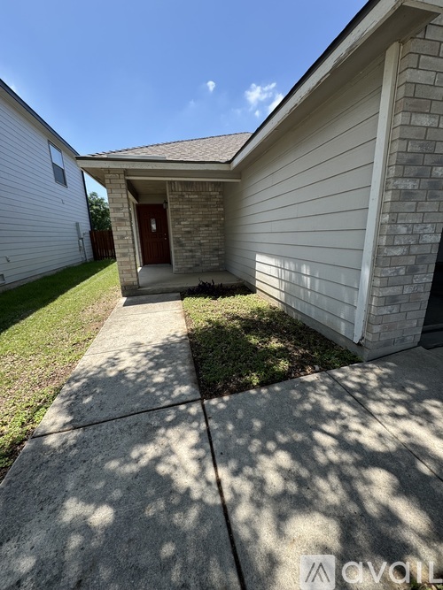 A house with a red door and a concrete walkway leading to it.