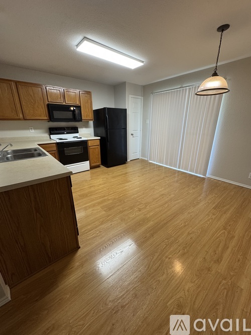 A kitchen with wooden cabinets and a black refrigerator.