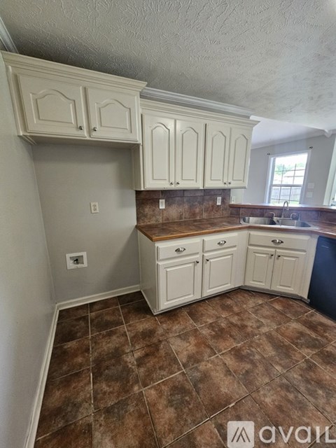 A kitchen with white cabinets and brown tiled floors.
