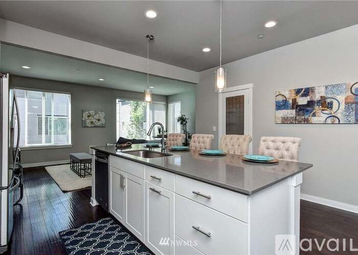 A kitchen with white cabinets and a black and white rug.