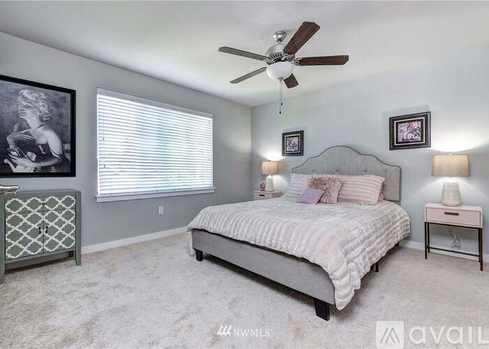 A bedroom with a bed, a ceiling fan, and a window with blinds.