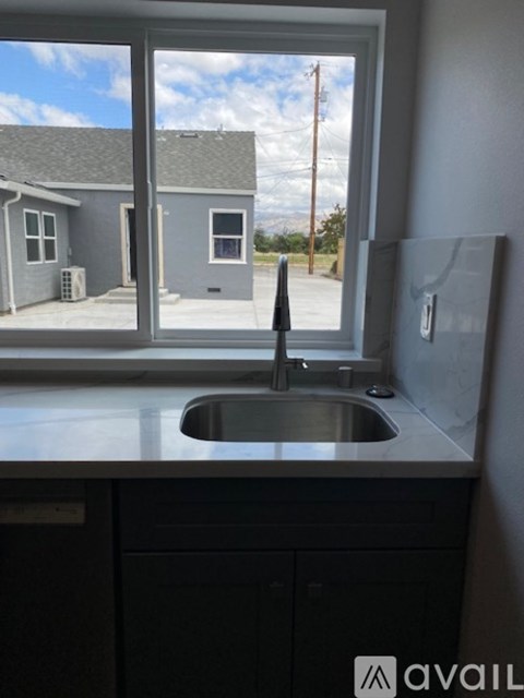 A kitchen sink with a window overlooking a house.