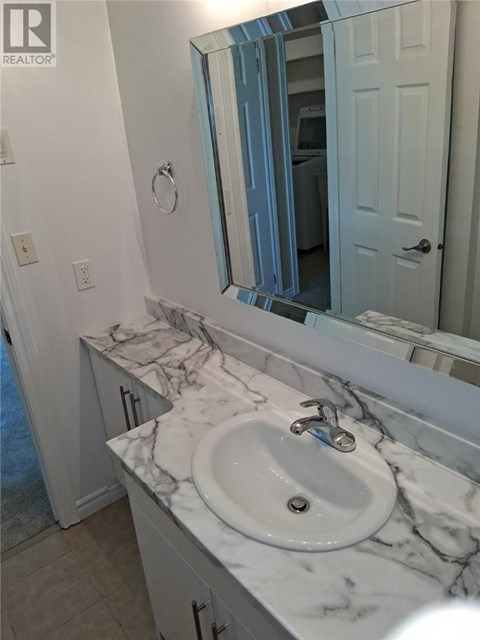 A bathroom with a marble countertop and a white sink.