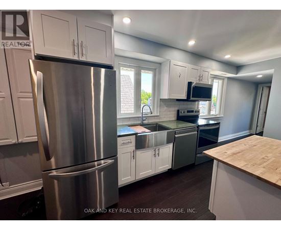 A kitchen with a stainless steel refrigerator and white cabinets.