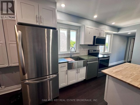 A kitchen with a stainless steel refrigerator and white cabinets.