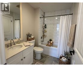 A bathroom with a white toilet, sink, and shower area.