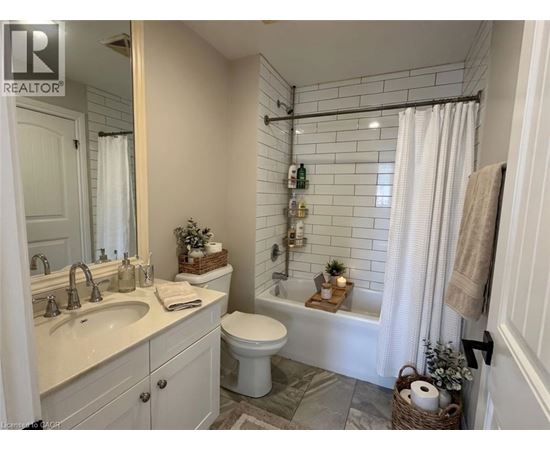 A bathroom with a white toilet, sink, and shower area.
