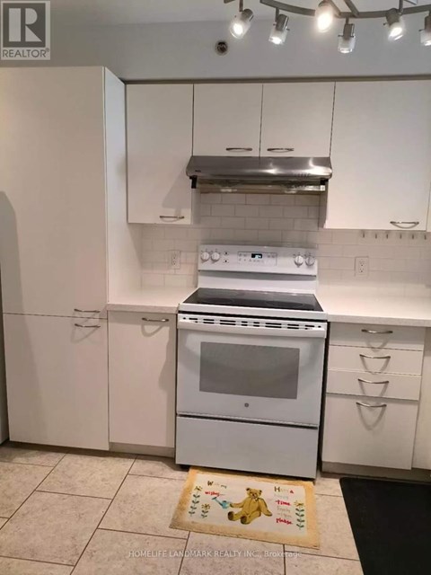 A white kitchen with a stove top oven and a range hood above it.