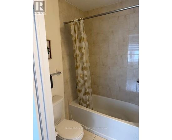 A bathroom with a toilet, shower, and a shower curtain.