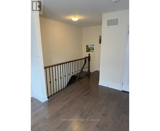 A dog is standing on a wooden floor in a room with white walls.