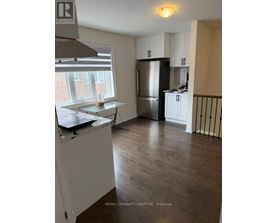 A kitchen with a refrigerator, cabinets, and a window.