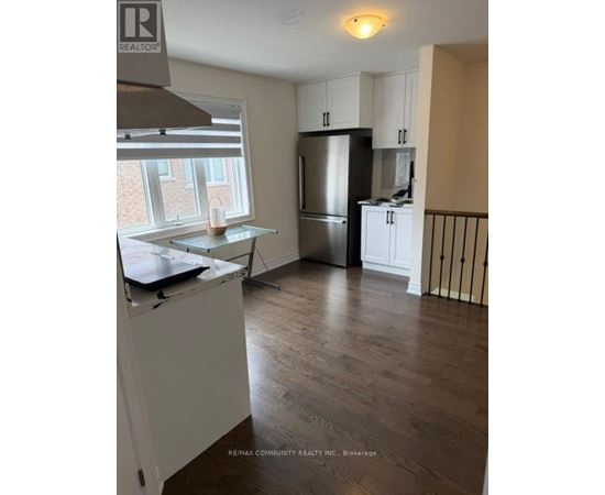 A kitchen with a refrigerator, cabinets, and a window.