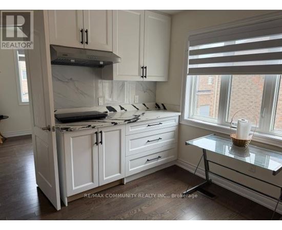 A kitchen with white cabinets and a marble island.