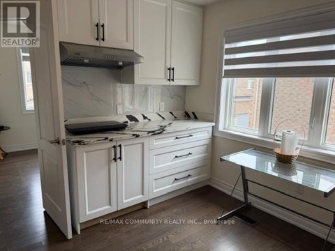 A kitchen with white cabinets and a marble island.