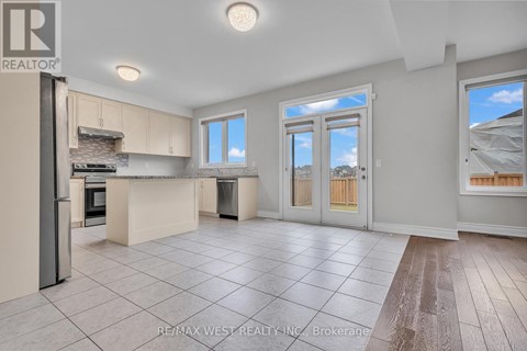 A spacious kitchen with a refrigerator, oven, and a dining table with chairs.