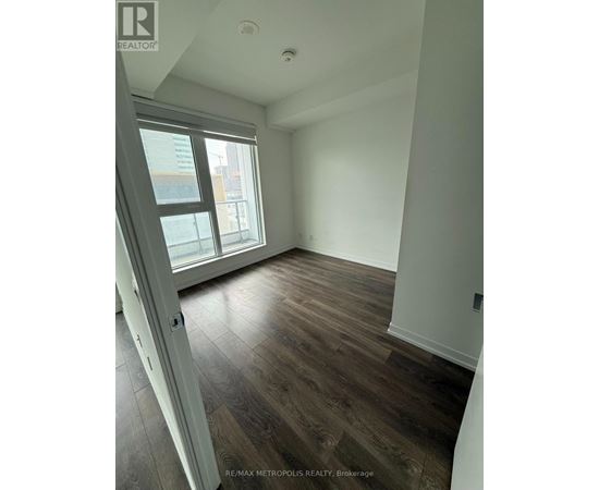 A room with a sliding glass door and wood flooring.