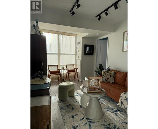 A living room with a brown couch and a white ottoman.