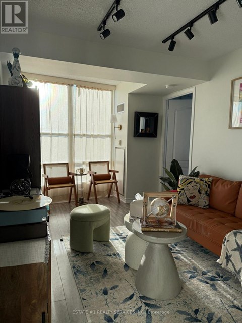 A living room with a brown couch and a white ottoman.