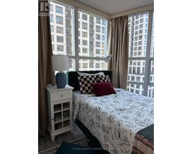 A bedroom with a large bed and a window overlooking a cityscape.