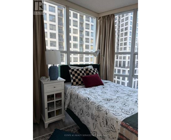 A bedroom with a large bed and a window overlooking a cityscape.