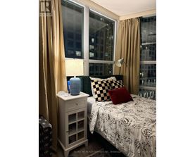 A bedroom with a bed, nightstand, and window.