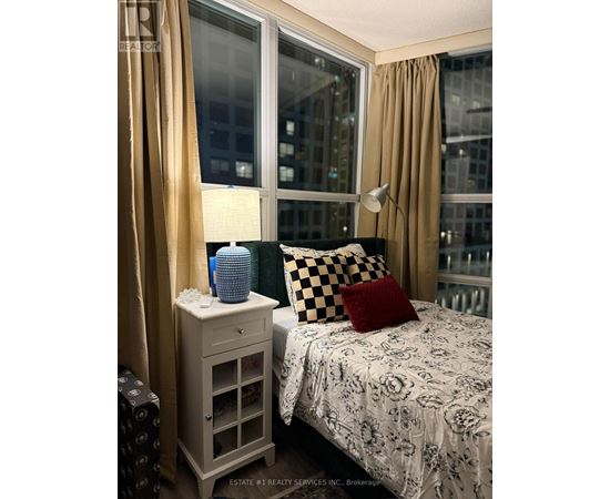 A bedroom with a bed, nightstand, and window.