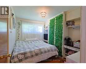 A bedroom with a Hello Kitty bedspread and a green plant on the wall.