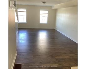 A room with wooden flooring and two windows.