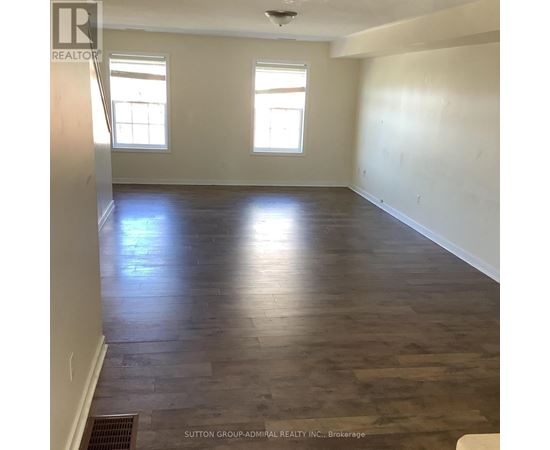 A room with wooden flooring and two windows.