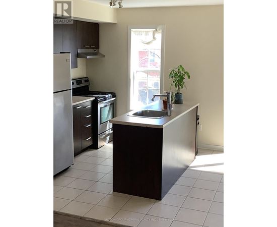 A kitchen with a refrigerator, oven, and sink.