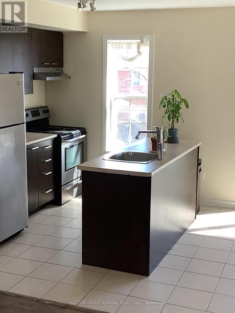 A kitchen with a refrigerator, oven, and sink.