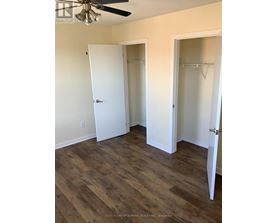 A room with wood flooring and two open closet doors.