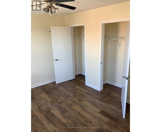 A room with wood flooring and two open closet doors.