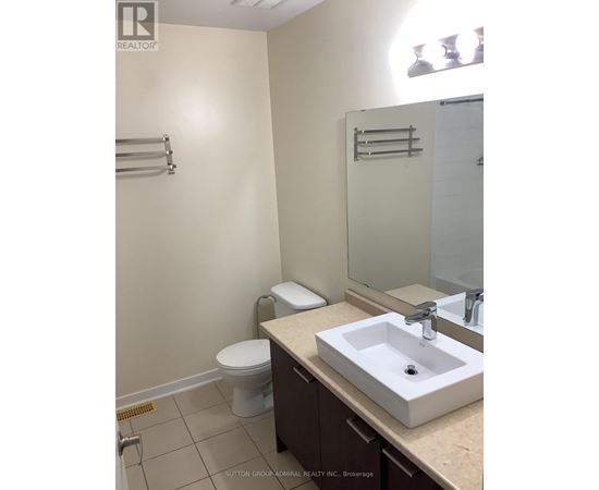 A bathroom with a toilet, sink and mirror.