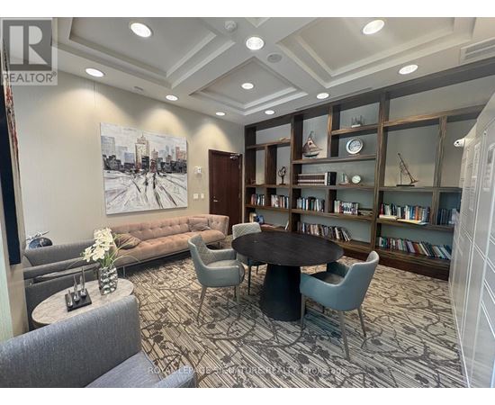 A living room with a large painting on the wall and a bookshelf filled with books.